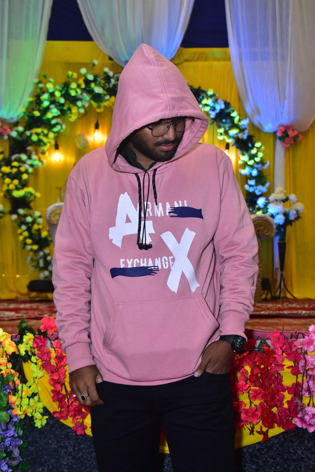 a man in a pink hoodie standing in front of a flower display